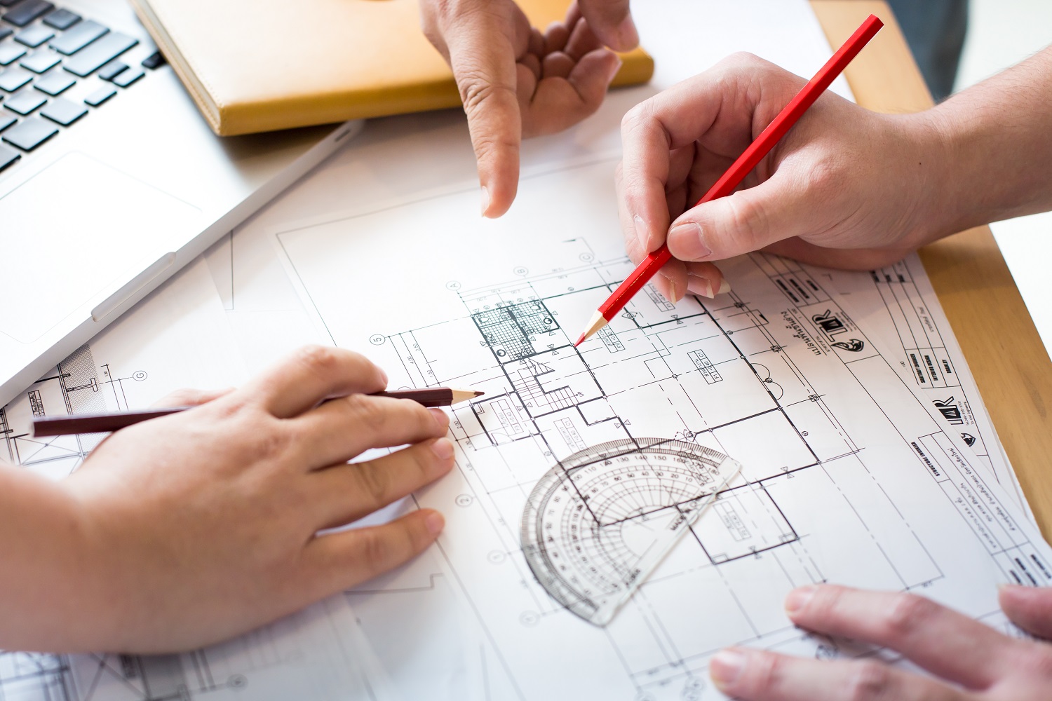 Architects discussing at the table with blueprint – Closeup on h